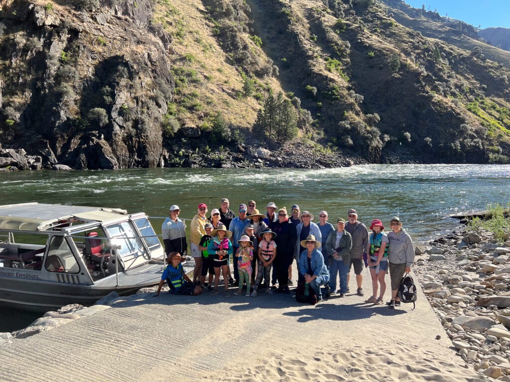 A large group of people stand in front of a jet boat during their Salmon River Scenic Tour with Whitewater Expeditions.